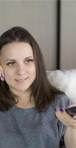 Woman sitting on couch using TV remote