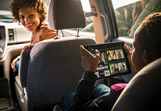 Lady and boy in car on tablet device with DISH app