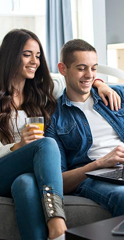 Young couple sitting on couch looking at laptop screen