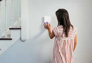 Woman adjusting Vivint thermostat on wall