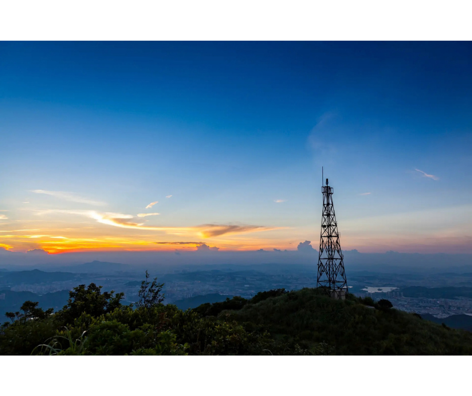 Cell tower overlooking a mountainous landscape at sunset