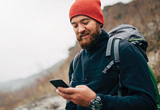 Man in hiking gear looking at mobile phone