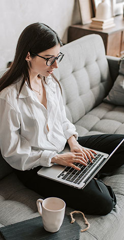 Woman sitting on couch typing on laptop