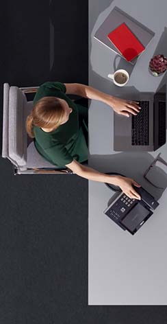 Woman sitting at desk with laptop and phone